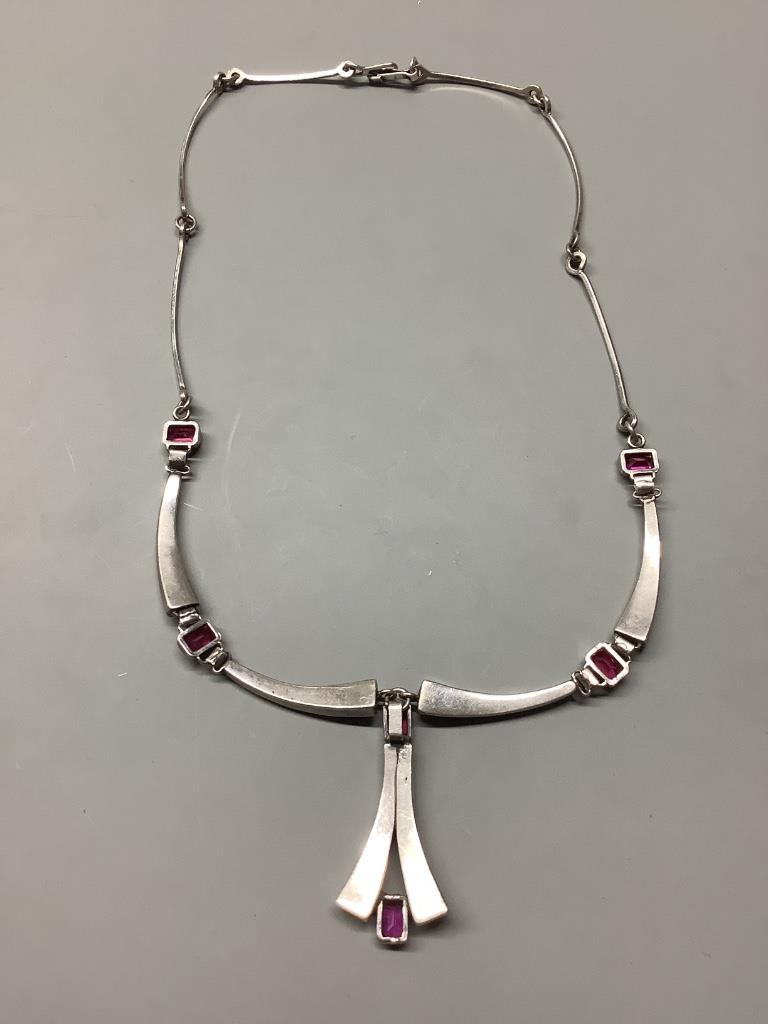 A modern stylish white metal and synthetic ruby set drop pendant necklace, 55 cm.